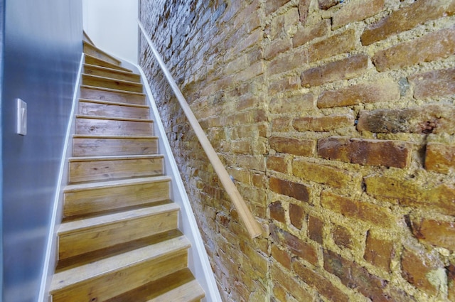 stairway featuring brick wall