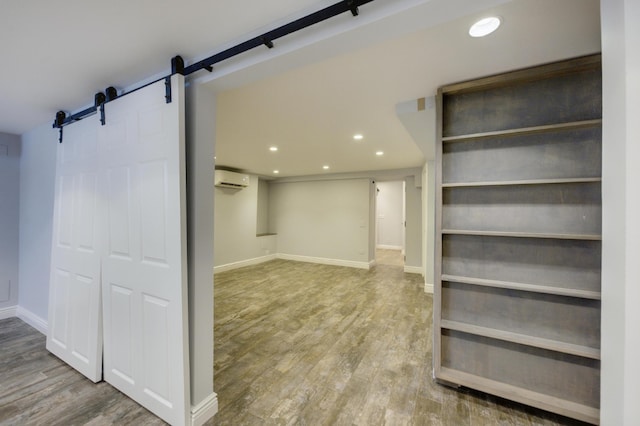 spacious closet with a barn door, a wall mounted AC, and hardwood / wood-style floors