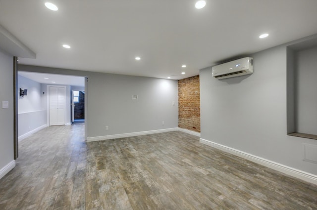 empty room featuring brick wall, a wall mounted AC, and light hardwood / wood-style flooring