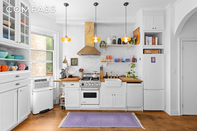 kitchen featuring white cabinetry, white appliances, wall chimney range hood, pendant lighting, and sink