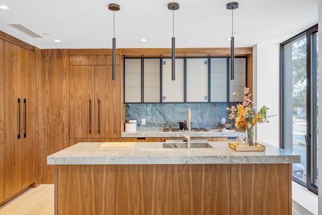 kitchen with tasteful backsplash, floor to ceiling windows, decorative light fixtures, and sink