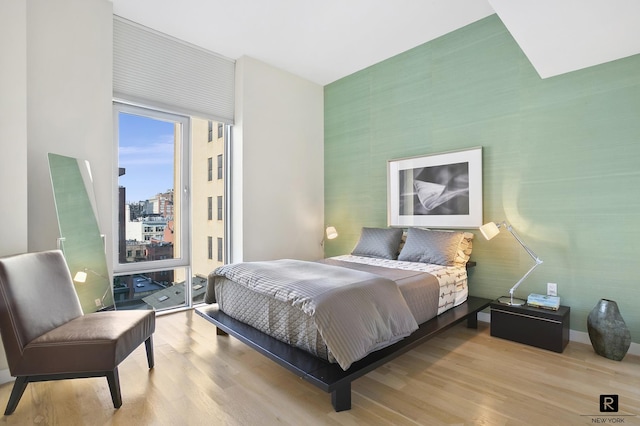 bedroom featuring a city view, wood finished floors, and access to exterior