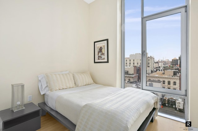 bedroom with a city view, wood finished floors, and expansive windows