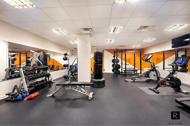 gym with visible vents, a paneled ceiling, and baseboards