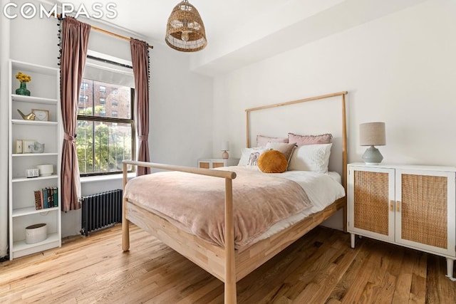 bedroom featuring radiator heating unit and hardwood / wood-style flooring