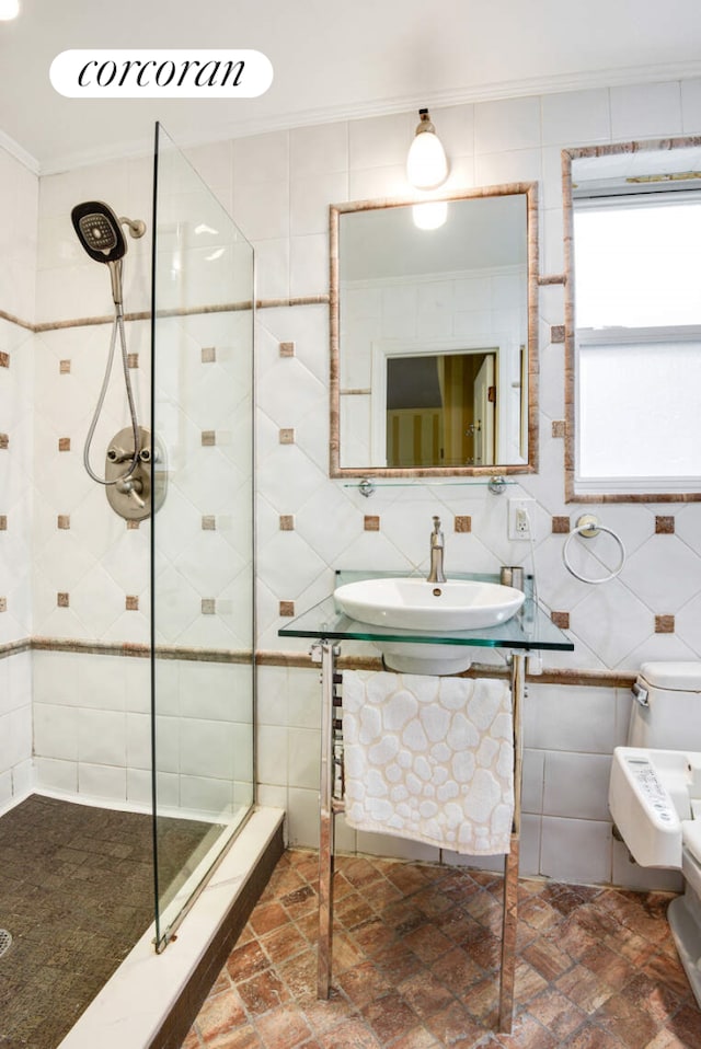 bathroom featuring toilet, a sink, tile walls, ornamental molding, and a stall shower