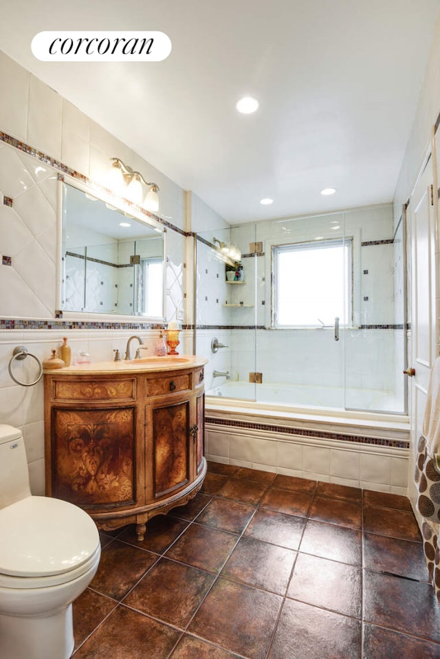 bathroom featuring toilet, vanity, tile walls, and tiled shower / bath