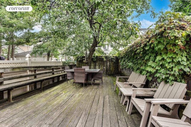 wooden terrace with outdoor dining area and fence