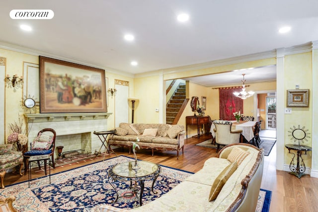 living room with an inviting chandelier, ornamental molding, and light hardwood / wood-style floors