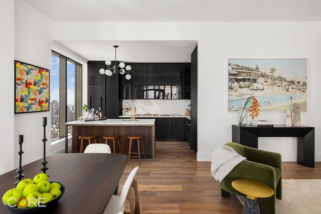 dining room with wood-type flooring, wet bar, and a notable chandelier