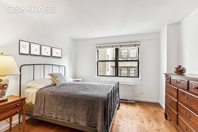 bedroom featuring radiator heating unit and light hardwood / wood-style floors