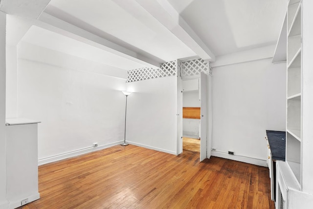 interior space featuring hardwood / wood-style floors, baseboards, and beamed ceiling