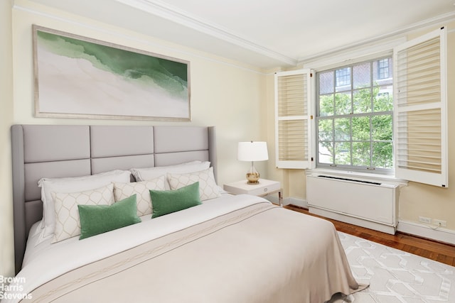 bedroom with baseboards, radiator heating unit, ornamental molding, and wood finished floors