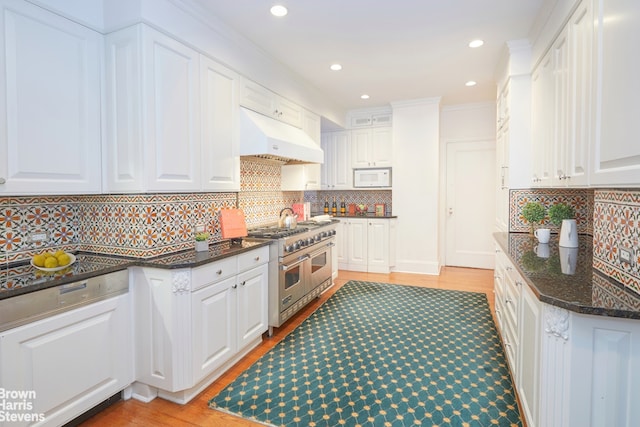 kitchen featuring range with two ovens, under cabinet range hood, white microwave, decorative backsplash, and recessed lighting