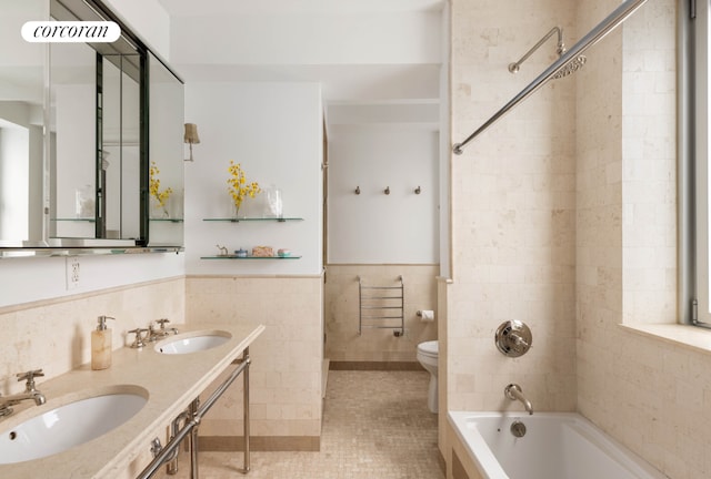 full bathroom with toilet, tiled shower / bath, tile walls, vanity, and tile patterned floors