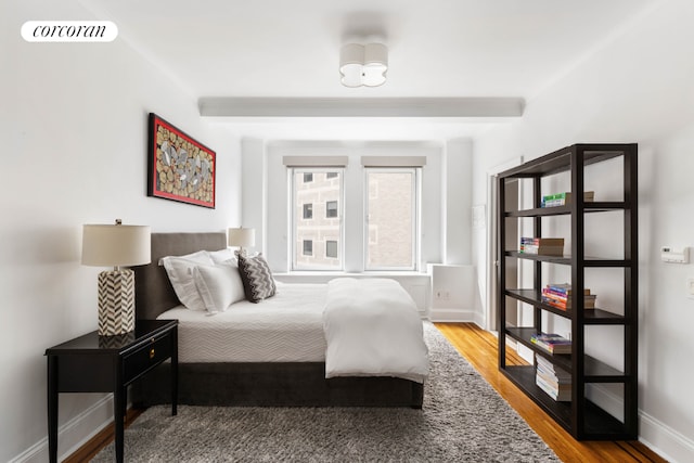 bedroom with beamed ceiling and hardwood / wood-style flooring