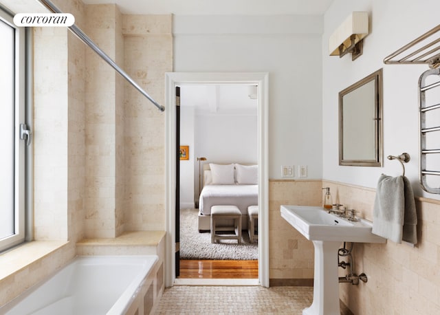 bathroom featuring tile walls, a bathing tub, and tile patterned flooring