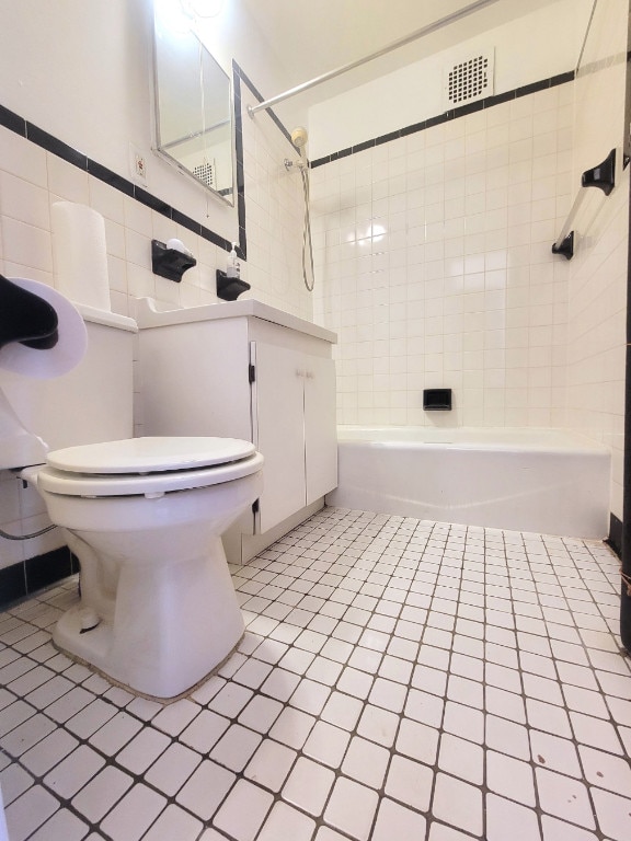 full bathroom with tiled shower / bath, vanity, tile patterned floors, and toilet