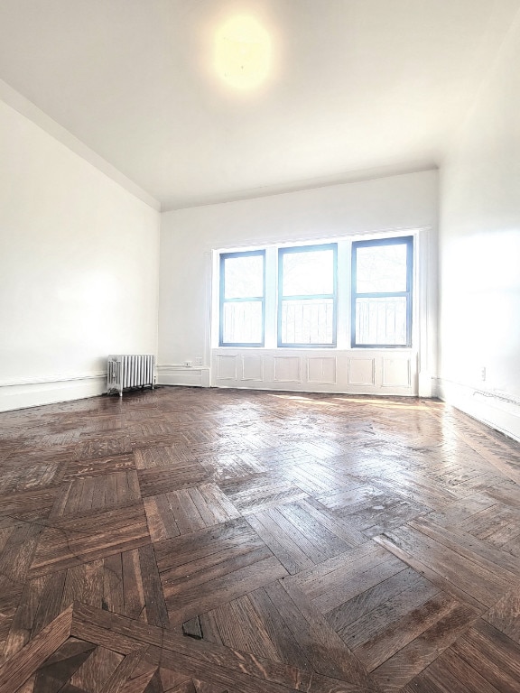 unfurnished room with radiator and dark parquet floors