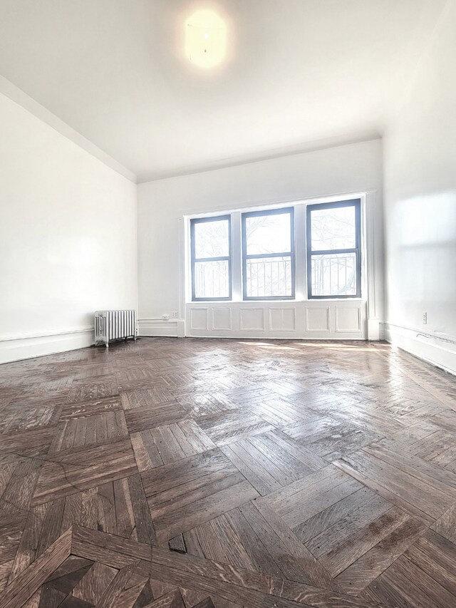 spare room with radiator and dark parquet floors