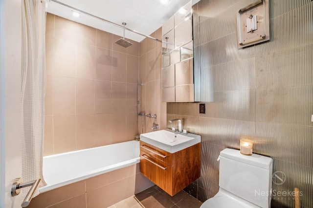 full bathroom with tile walls, vanity, tile patterned floors, toilet, and shower / bath combo with shower curtain