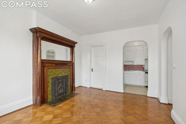 unfurnished living room featuring a tile fireplace and light parquet floors