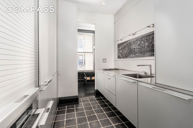 kitchen featuring light countertops, dark tile patterned flooring, a sink, and white cabinets