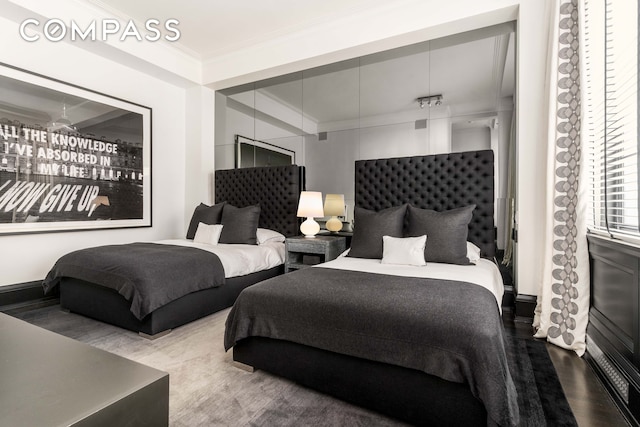 bedroom with ornamental molding and wood finished floors