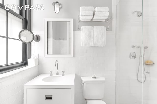 full bath with tile walls, toilet, a shower stall, and vanity