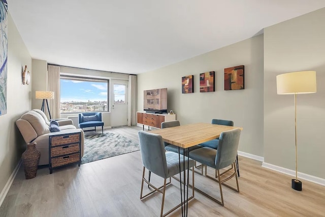 dining space with baseboards and light wood finished floors