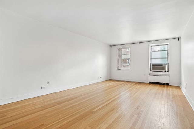 empty room featuring cooling unit, radiator, and light hardwood / wood-style flooring