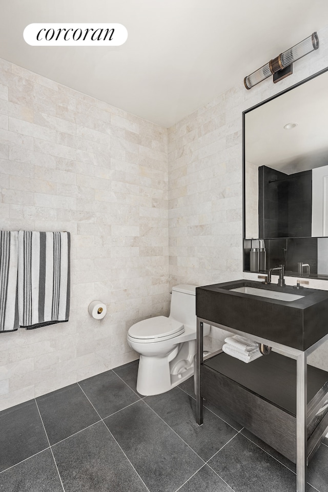 bathroom featuring toilet, vanity, tile walls, and tile patterned floors