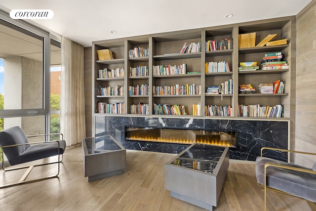 living area with a fireplace, wood finished floors, visible vents, and floor to ceiling windows