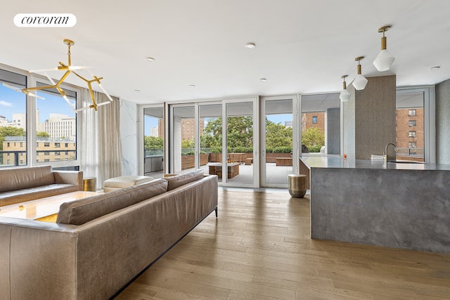 living area featuring a wealth of natural light, wood-type flooring, floor to ceiling windows, and visible vents