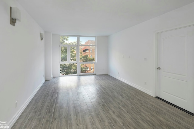 unfurnished room featuring wood finished floors, baseboards, and expansive windows