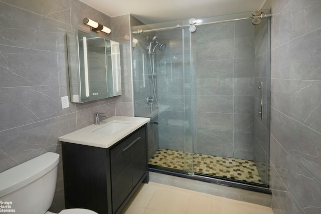 full bathroom with a shower stall, tile walls, toilet, tile patterned floors, and vanity