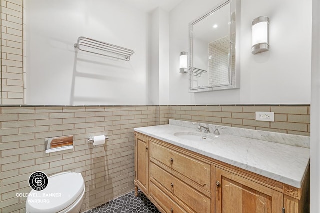 bathroom with tile patterned floors, tile walls, toilet, and vanity