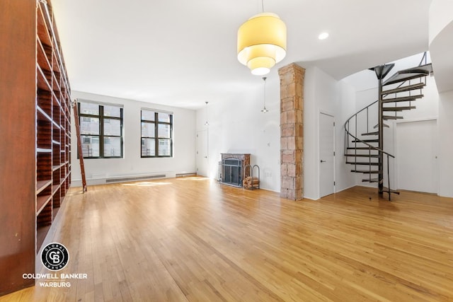 unfurnished living room with hardwood / wood-style flooring, a baseboard radiator, and a fireplace