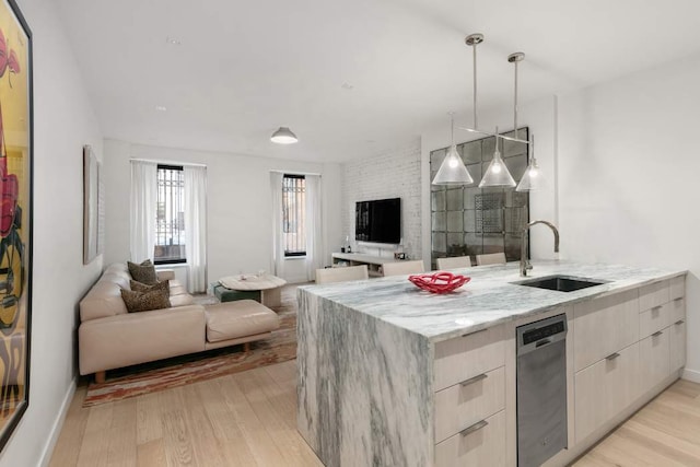 kitchen featuring pendant lighting, sink, stainless steel dishwasher, light stone counters, and light hardwood / wood-style floors