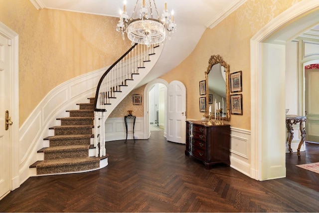 entryway featuring ornamental molding, a chandelier, and dark parquet flooring