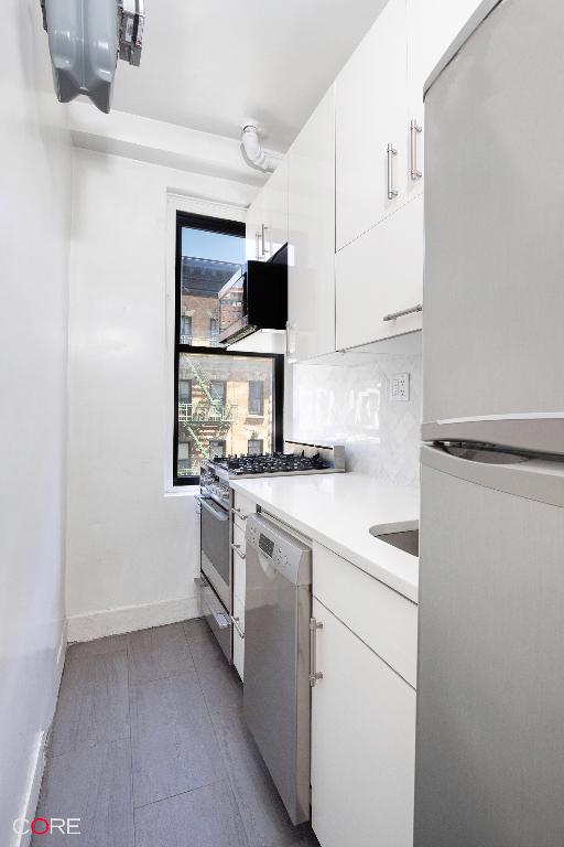 kitchen with appliances with stainless steel finishes, white cabinets, and decorative backsplash