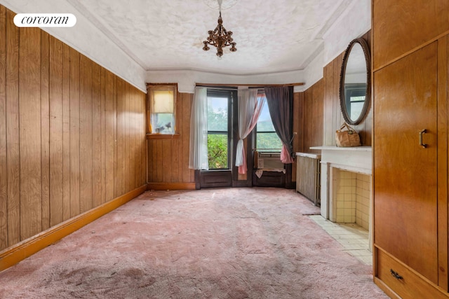 unfurnished room featuring light colored carpet, a chandelier, a textured ceiling, and wood walls