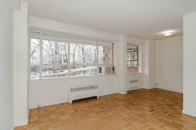 unfurnished room with baseboards, a healthy amount of sunlight, and radiator