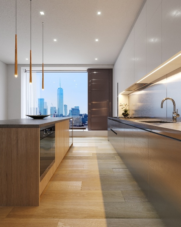 kitchen featuring light wood-type flooring, hanging light fixtures, oven, white cabinets, and sink