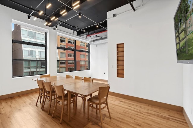 dining space featuring wood-type flooring and a high ceiling