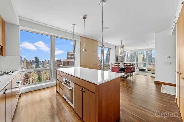 kitchen featuring a center island, wood-type flooring, white gas stovetop, decorative light fixtures, and a chandelier