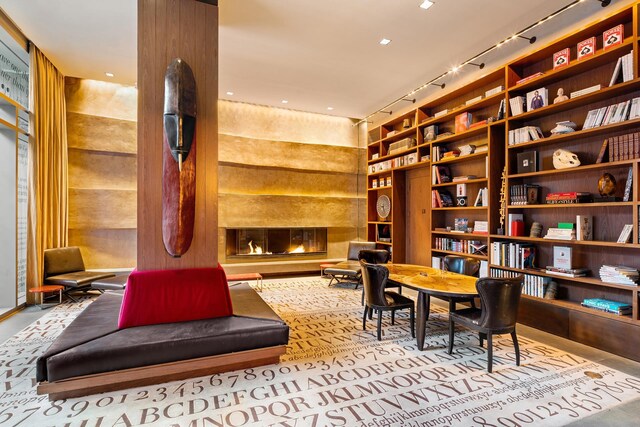 living area featuring track lighting, built in features, and wood walls