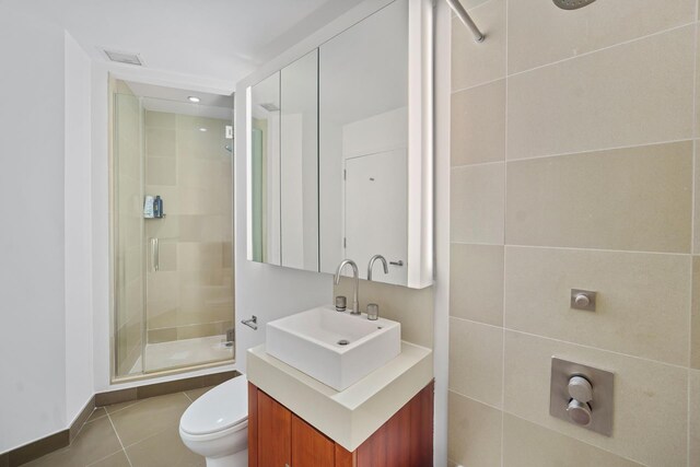 bathroom featuring vanity, toilet, an enclosed shower, and tile patterned flooring