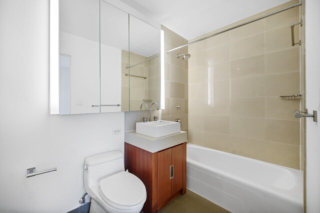 full bathroom with tiled shower / bath combo, vanity, tile patterned floors, and toilet