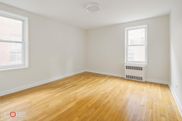 spare room with radiator heating unit and light wood-type flooring